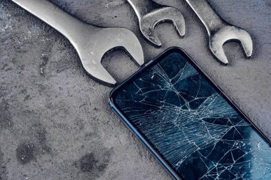 Gri arkaplanda tamir araçları ile çökmüş akıllı telefon