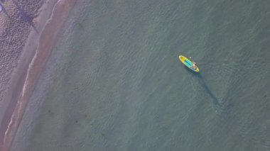 Havadan drone görüntüsü, bir adamın sup standında kürek çekerken görüntüsü. 