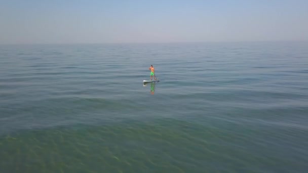 从空中俯瞰一个男子在水底看板上划桨的景象 — 图库视频影像