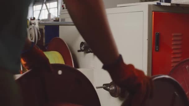 Onherkenbare werknemer rolt een haspel met kabel in kabel productie-installatie, close-up — Stockvideo