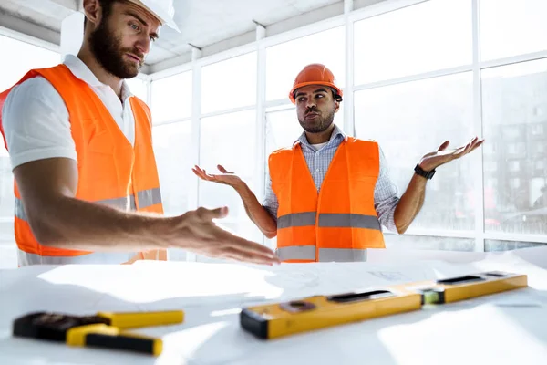 Två ingenjörer man tittar på projektplan på bordet i byggarbetsplatsen — Stockfoto