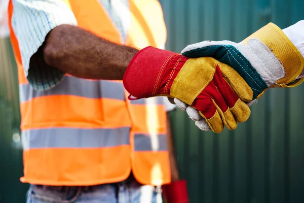 Close up foto de dois homens construtores em workwear apertando as mãos — Fotografia de Stock