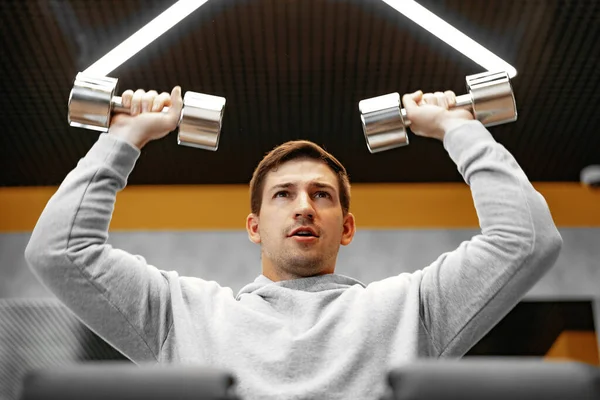 Déterminé beau jeune homme travaillant dans la salle de gym avec haltères — Photo