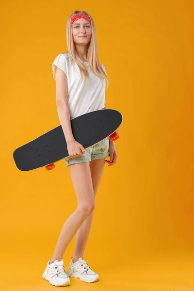 Mooie en mode tiener poseren met een skateboard in de studio — Stockfoto