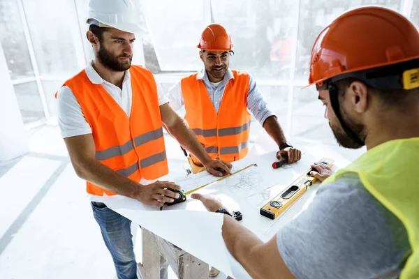 Två ingenjörer man tittar på projektplan på bordet i byggarbetsplatsen — Stockfoto