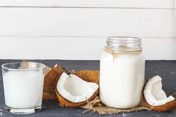 Coco y vaso de leche de coco sobre fondo de madera — Foto de Stock