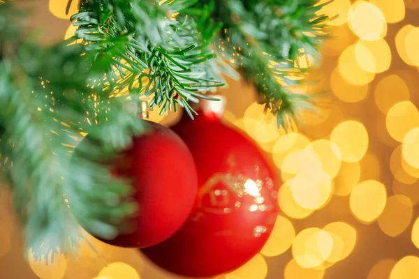 Червоний різдвяний м'яч, що звисає на гілці ялинки над золотим фоном вогнів боке — стокове фото
