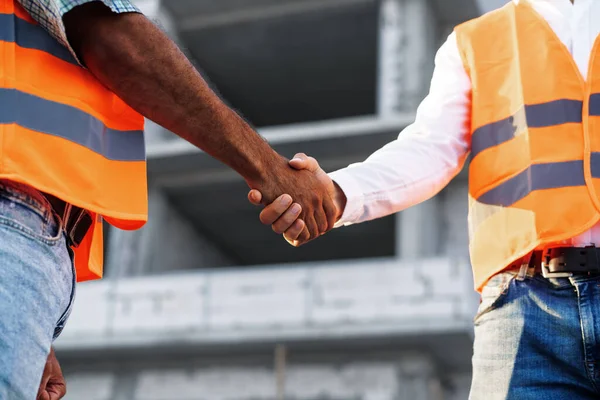 Két munkaruhás mérnök kezet rázott az építkezéssel.. — Stock Fotó
