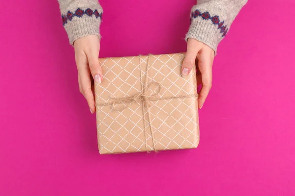 Gift box in female hands on pink background — Stock Photo, Image