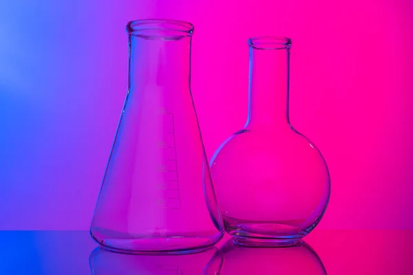 Chemical glassware close up on neon pink-purple background — Stock Photo, Image