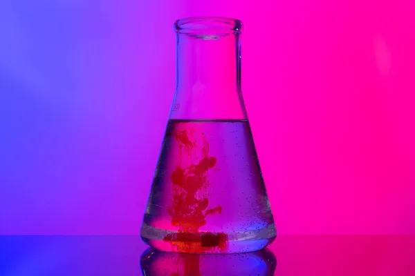 Лабораторні скляні трубки з хімікатами на яскраво-рожевому фоні — стокове фото