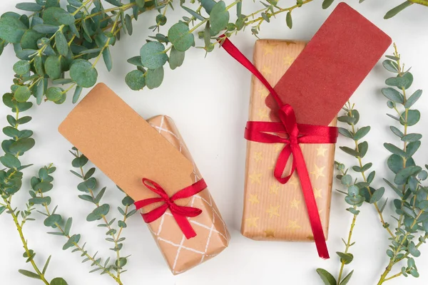 Geschenkdozen verpakt in ambachtelijk papier met eenvoudig decor van groene plantentakken — Stockfoto