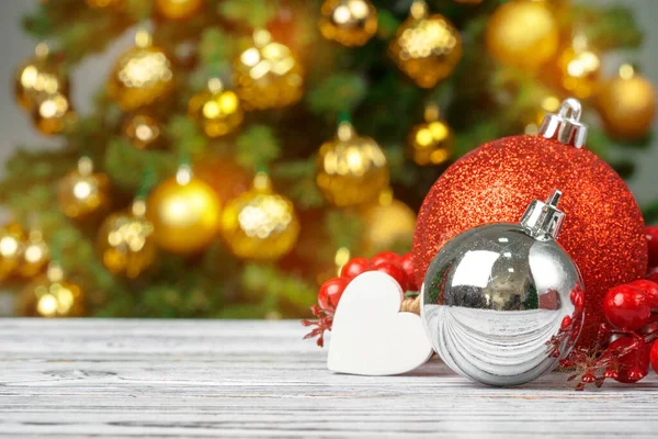 Bola de Navidad sobre mesa de madera contra fondo borroso árbol de navidad decorado — Foto de Stock