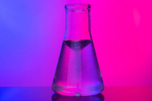 Chemical glassware close up on neon pink-purple background — Stock Photo, Image