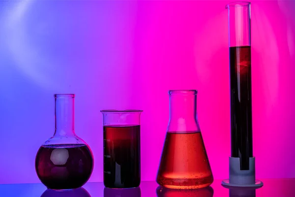 Tubos de vidro de laboratório com produtos químicos sobre fundo rosa brilhante — Fotografia de Stock