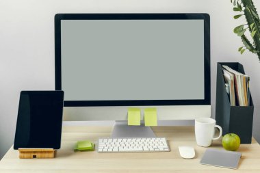 Ofis masasında malzemelerle birlikte beyaz ekranlı bilgisayar monitörü