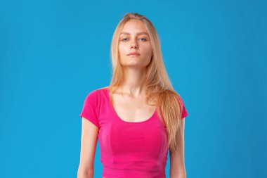 Mavi arka planda genç, sarışın, beyaz kadın portresi.