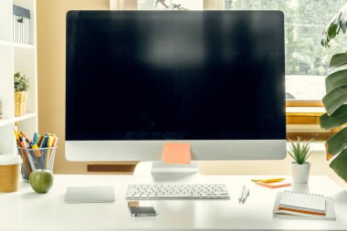 Ofis ya da ev işi. Ofis masasında malzemelerle siyah ekranlı bilgisayar monitörü
