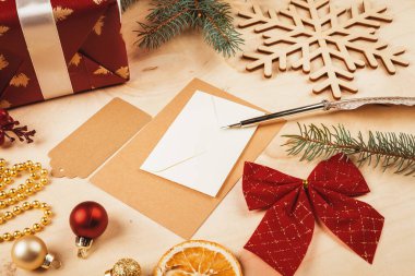 Noel süsleriyle çevrili karşılama mektubu, zarf ve tüy.
