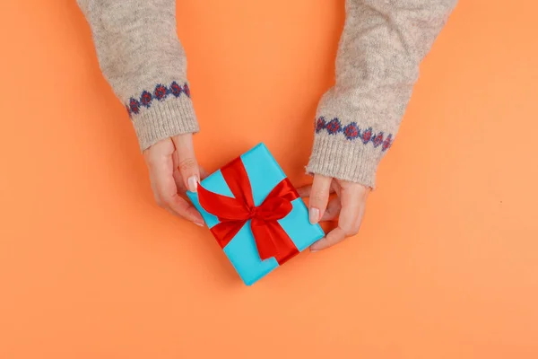Manos de mujer sosteniendo caja de regalo sobre fondo naranja —  Fotos de Stock