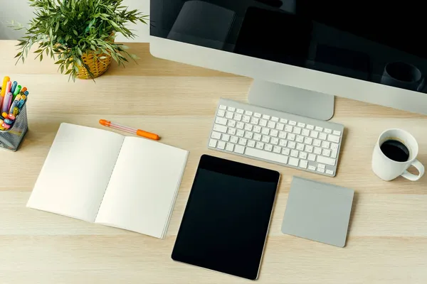 Vista superior de la mesa de trabajo con computadora, bloc de notas, taza de café y suministros — Foto de Stock
