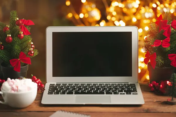Drewniane biurko z komputerem z czystym ekranem na tle rozmytych świateł Bożego Narodzenia — Zdjęcie stockowe