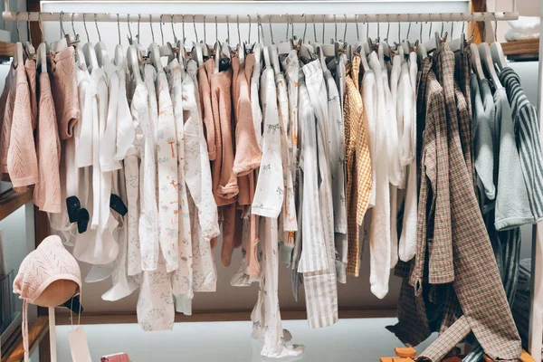 Perchas con diferentes ropas femeninas en una tienda de moda — Foto de Stock