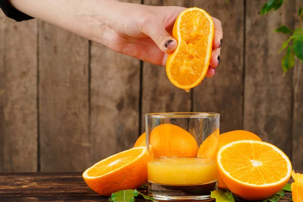 Woman hand squeezes orange juice close up — Stock Photo, Image