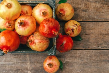 Tahta arka plandaki eski bir kutuda taze nar.