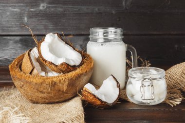 Siyah ahşap arka plan üzerinde kırık hindistan cevizi ve hindistan cevizi sütü