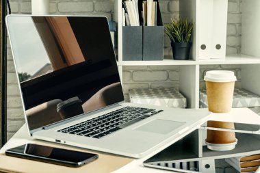 Ofis malzemeleriyle birlikte çalışma masasında bir ışık odasında dizüstü bilgisayar.