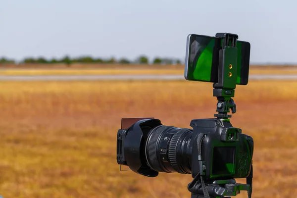 Câmera moderna em um tripé no campo — Fotografia de Stock