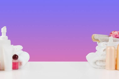 Havlu yığını, beyaz masada şampuanlı şişeler.