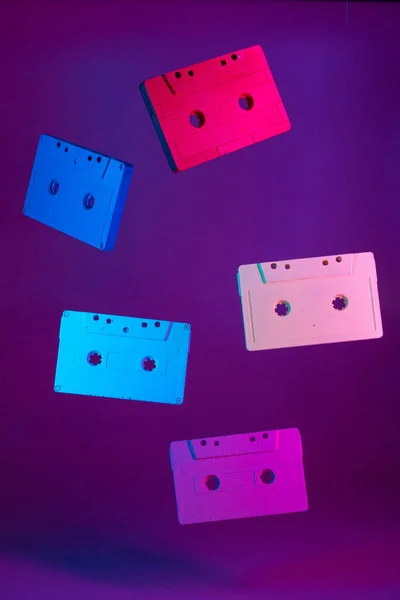 Farbige Audiokassetten hängen vor violettem Hintergrund in der Luft — Stockfoto