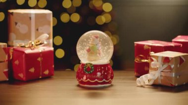 Noel kar küresi ve Noel hediyeleri masada