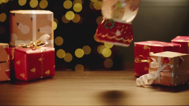 Karácsonyi hógömb és karácsonyi ajándékok az asztalon — Stock videók