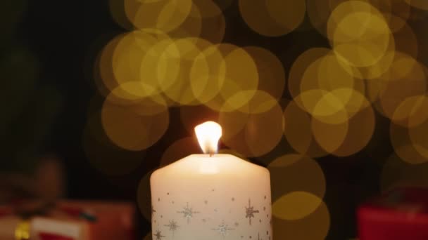 Різдвяна свічка горить на розмитому фоні — стокове відео