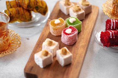 Beyaz dokulu arka planda çeşitli Türk tatlıları ve bir fincan çay