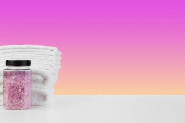 Banyo havluları ve spa tuzu beyaz masada.