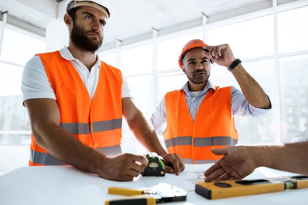 Dois engenheiros homem olhando para o plano do projeto na mesa no canteiro de obras — Fotografia de Stock
