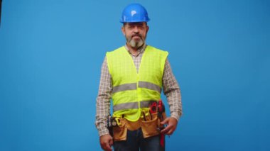 Kıdemli ustabaşı mavi arka plana karşı bir araç tutuyor.