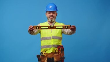 Kıdemli ustabaşı mavi arka plana karşı bir araç tutuyor.