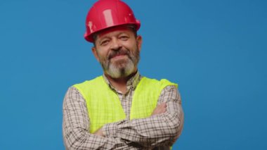 Mavi arka planda yelek ve şapka giymiş gülümseyen kıdemli mimar.