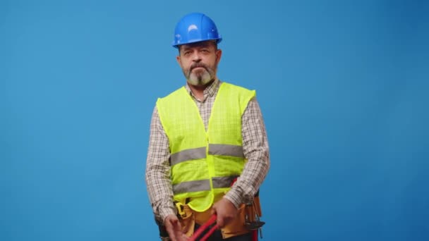 Starší muž předák držení nástroj proti modré pozadí — Stock video