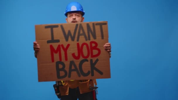 Senior man builder in hardhat holding cardboard tabliczka uderzające na niebieskim tle — Wideo stockowe