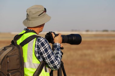 Sarı yelekli adam havaalanında uçak gözlemi yapıyor.