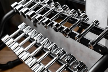 Spor salonunda vücut geliştirme için raflarda duran metal dambıllar.