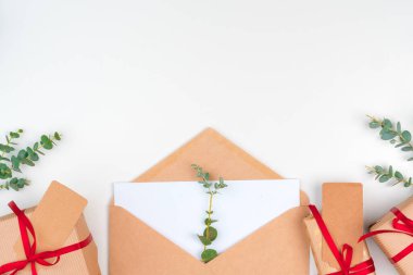 Kırmızı fiyonklu bir Noel hediyesi ve beyaz ahşap arka planda tebrik kartı.