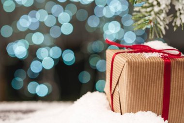 Tahta masada Noel hediyesi olan karlı bir kompozisyon.