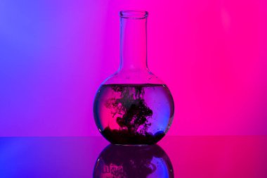 Parlak pembe arka planda kimyasallarla dolu laboratuvar cam tüpleri.